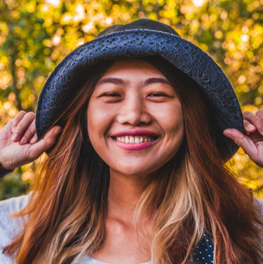 Young girl smiling and holding her hat