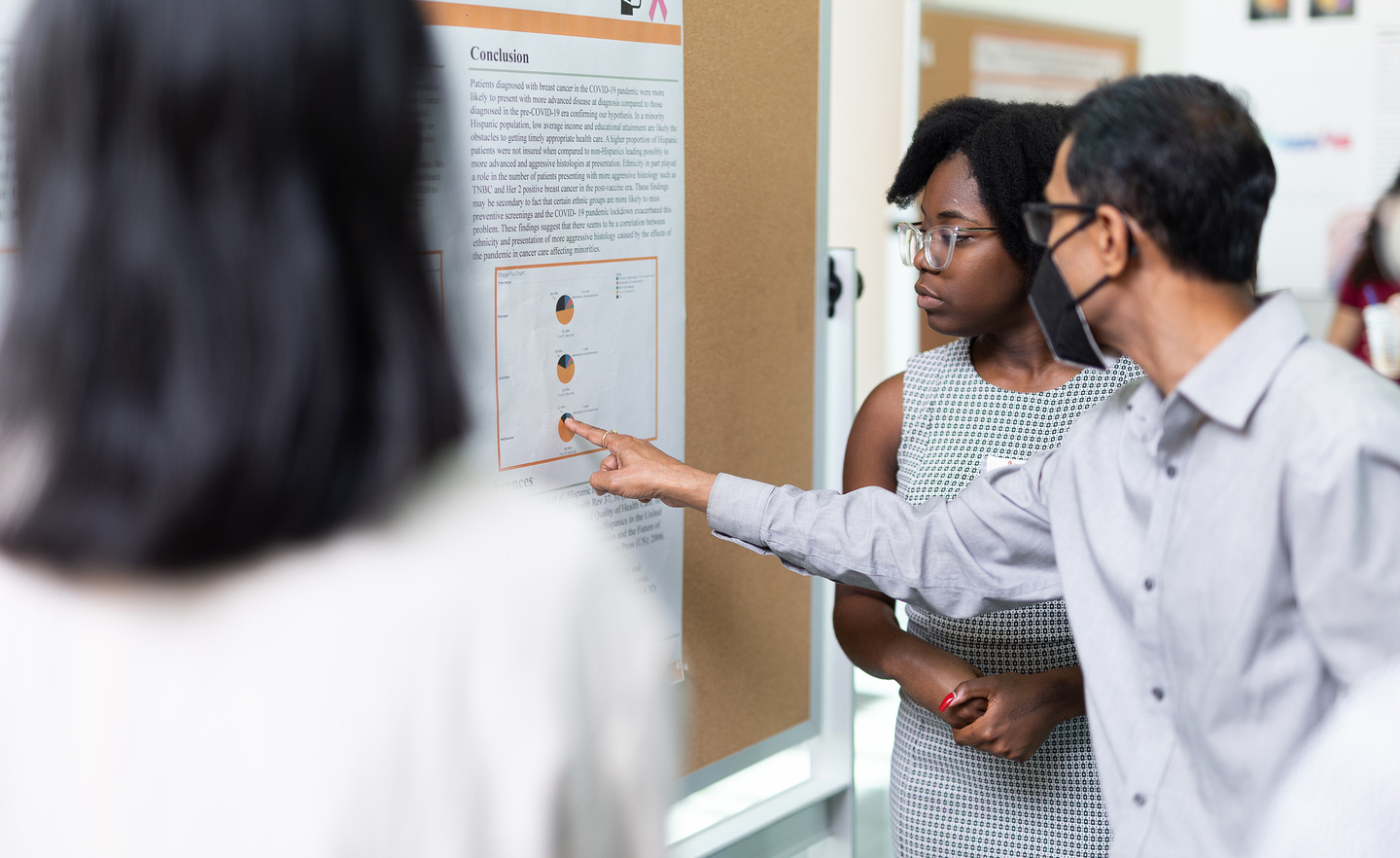 Two student interns looking and pointing at a poster presentation.