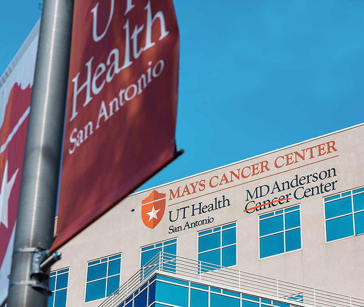 the Mays Cancer Center building with a UT Health San Antonio flag