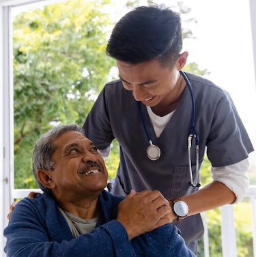 Patient in wheelchair smiling at cancer treatment nurse