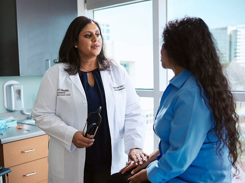 Sukeshi Patel Arora, MD, speaks with a woman in blue shirt in a clinical space.